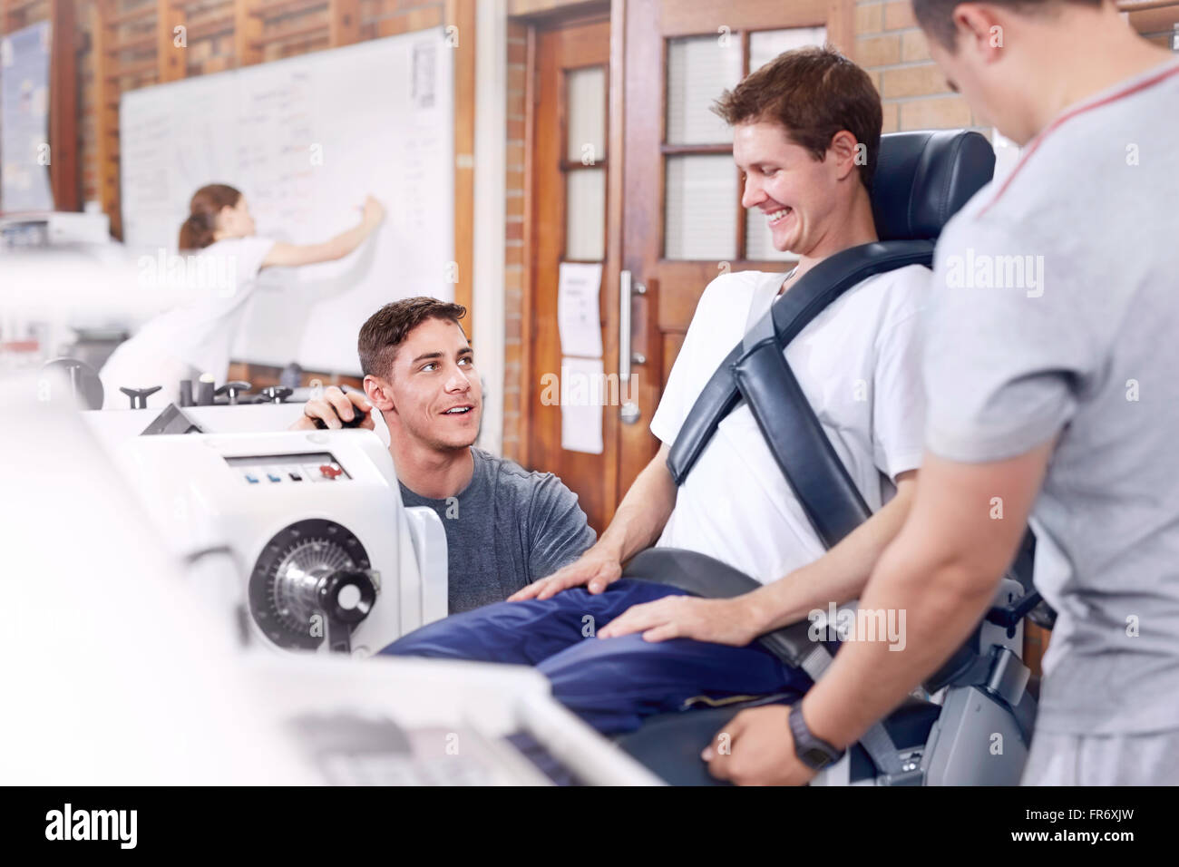 Physical therapists guiding man at machinery Stock Photo