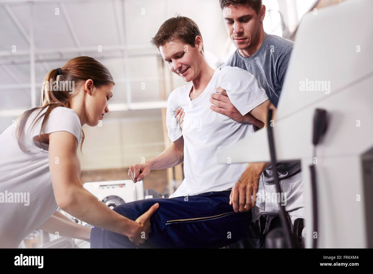 Physical therapists lifting man Stock Photo