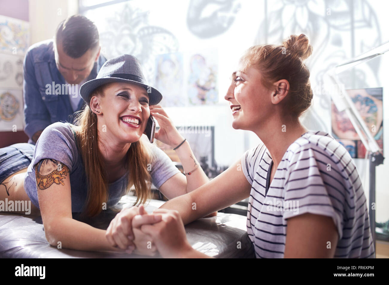 Smiling woman with friend getting tattoo Stock Photo