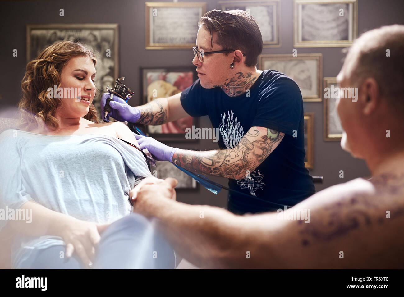 Tattoo artist tattooing woman’s shoulder Stock Photo