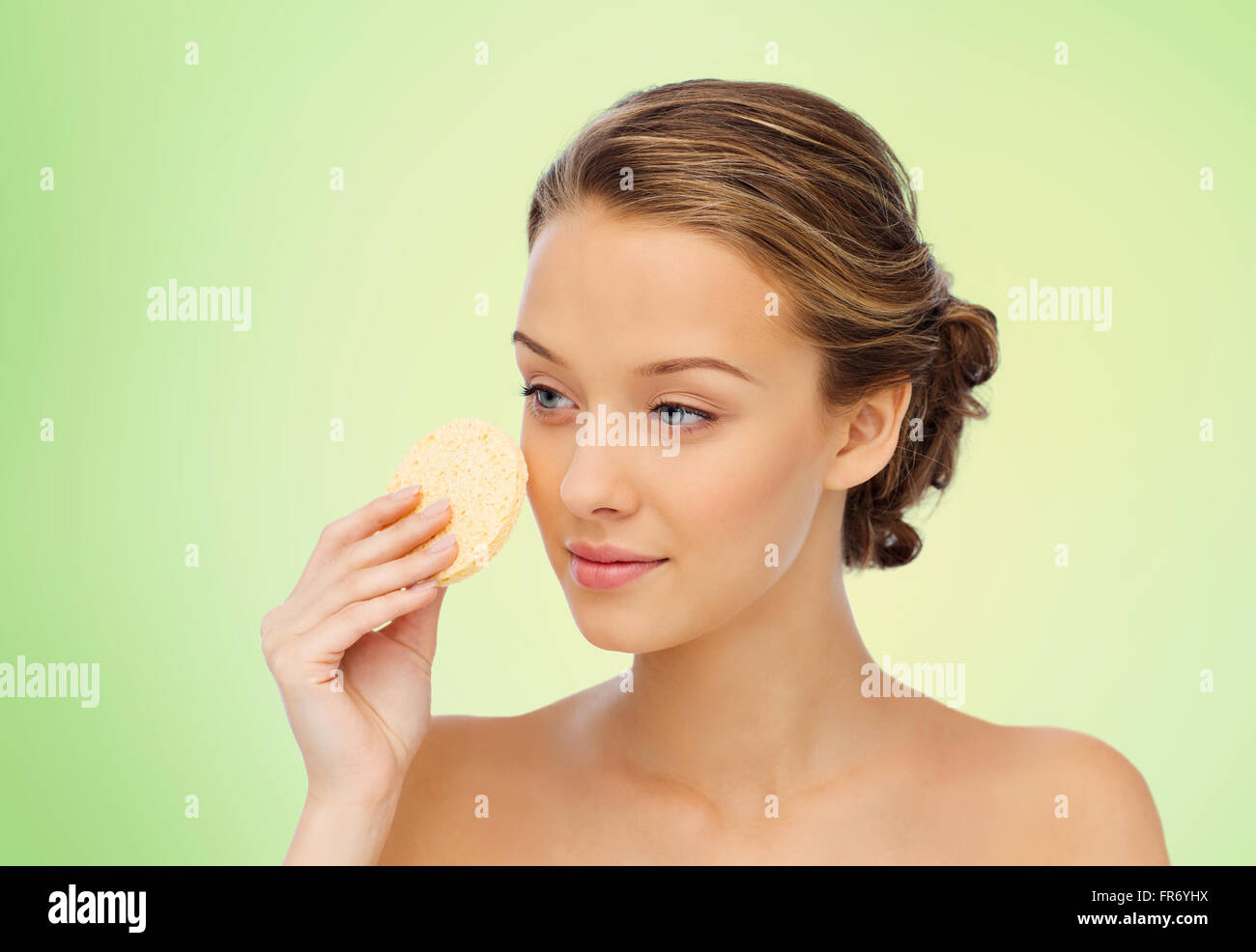 young woman cleaning face with exfoliating sponge Stock Photo