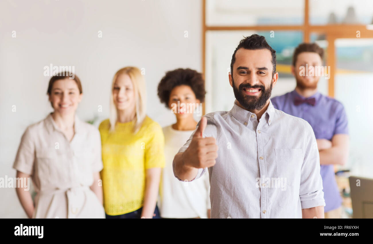 happy man showing thumbs up over team in office Stock Photo - Alamy