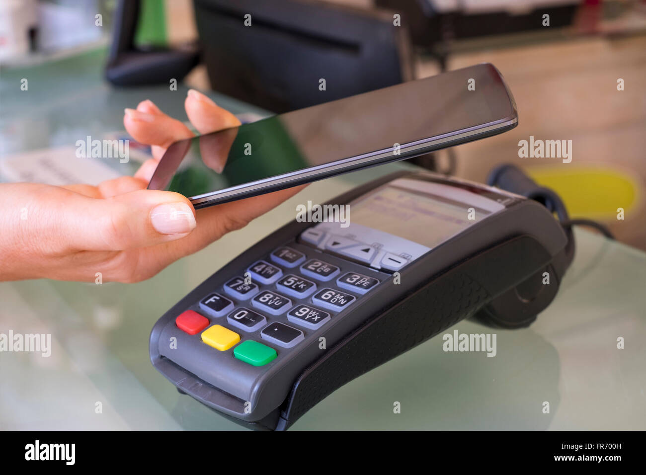 Woman paying with NFC technology on mobile phone, beautician, shop, market. Contactless payment Stock Photo