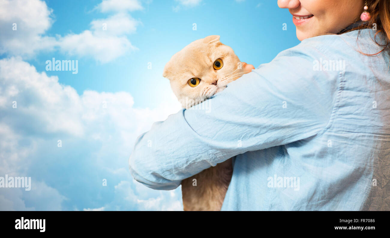 happy woman holding scottish fold cat over sky Stock Photo