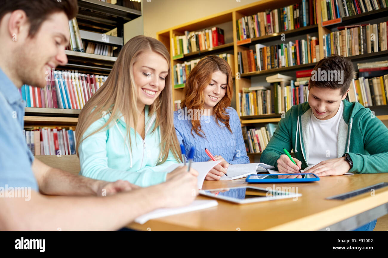 happy students with tablet pc in library Stock Photo - Alamy