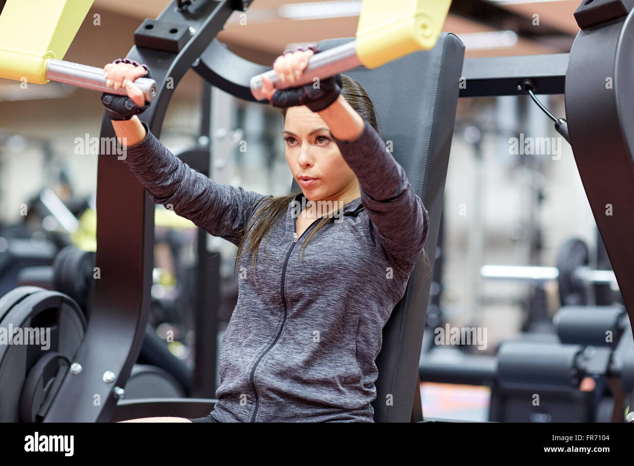 Woman flexing muscles on seated chest press machine in gym. Healthy  lifestyle concept Stock Photo - Alamy