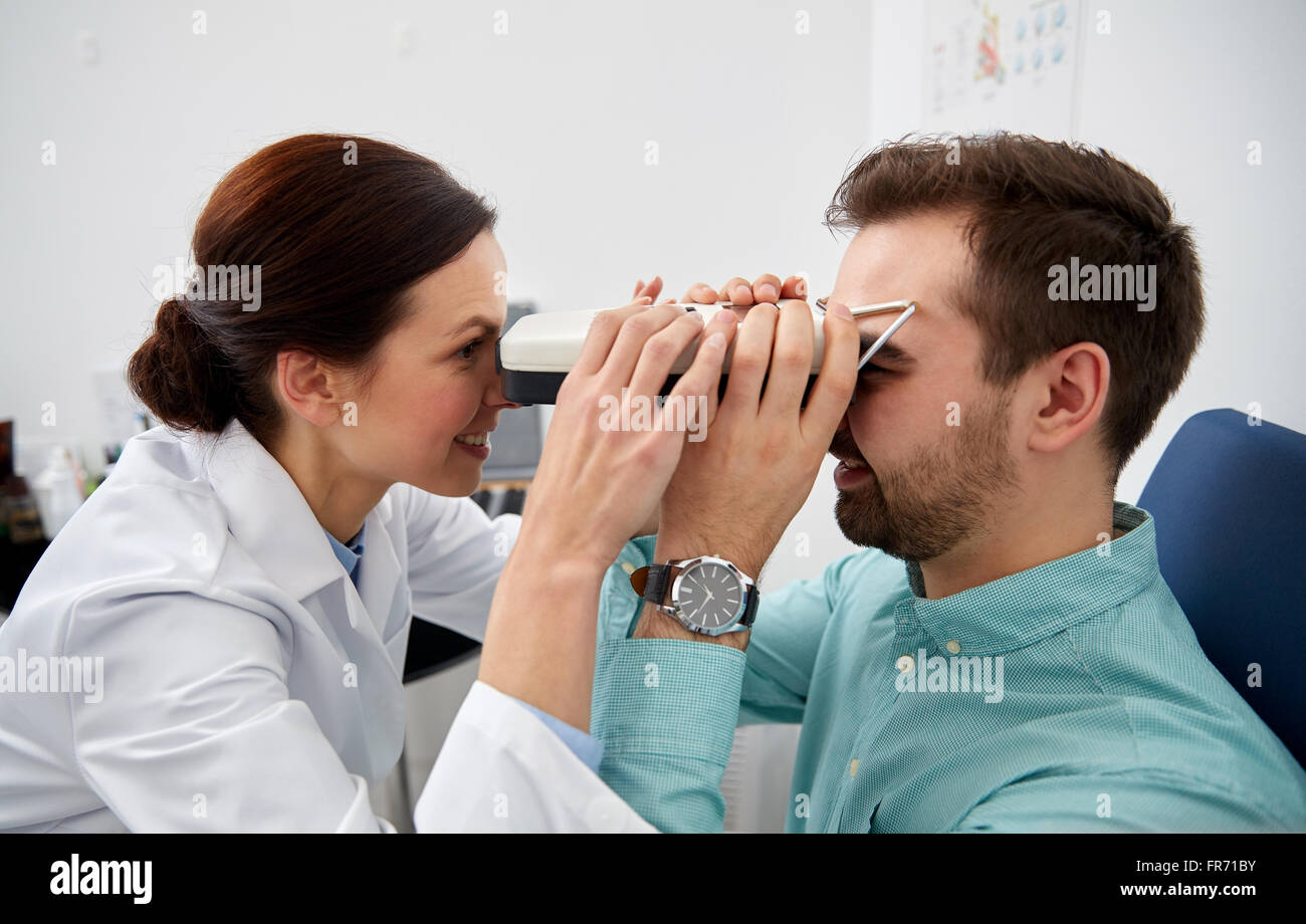 optician with pupilometer and patient at eye clinic Stock Photo