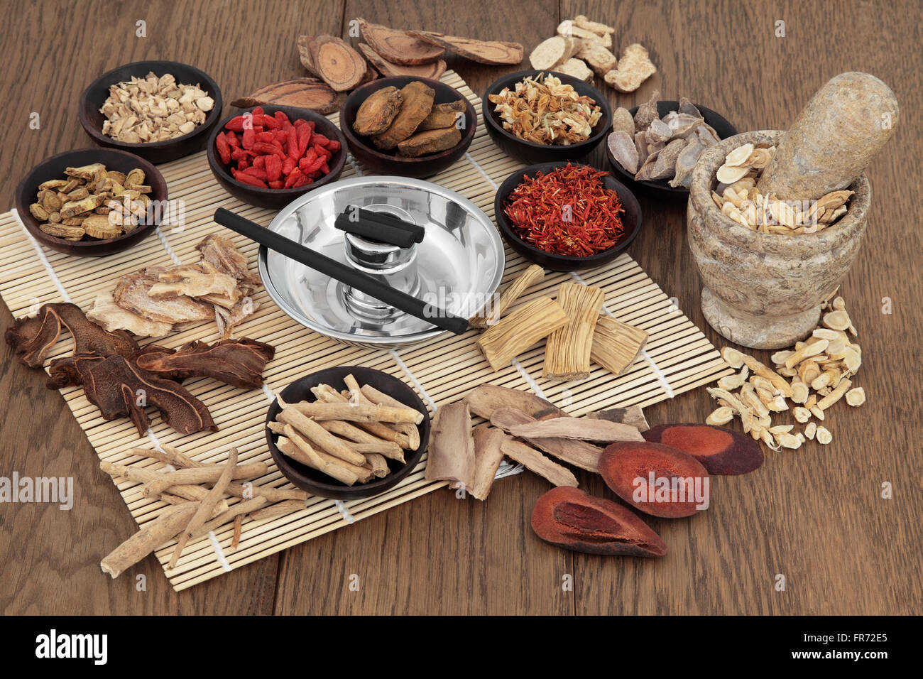 Moxa sticks and chinese herbs used in traditional herbal medicine with mortar and pestle over bamboo and oak background. Stock Photo