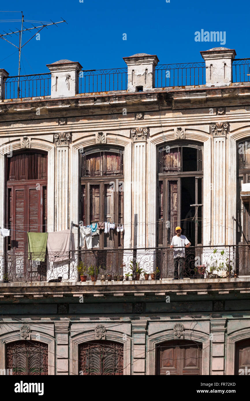 Daily life in Cuba - Cuban man leaning on balcony railings with washing hung out to dry at Havana, Cuba, West Indies, Caribbean, Central America Stock Photo