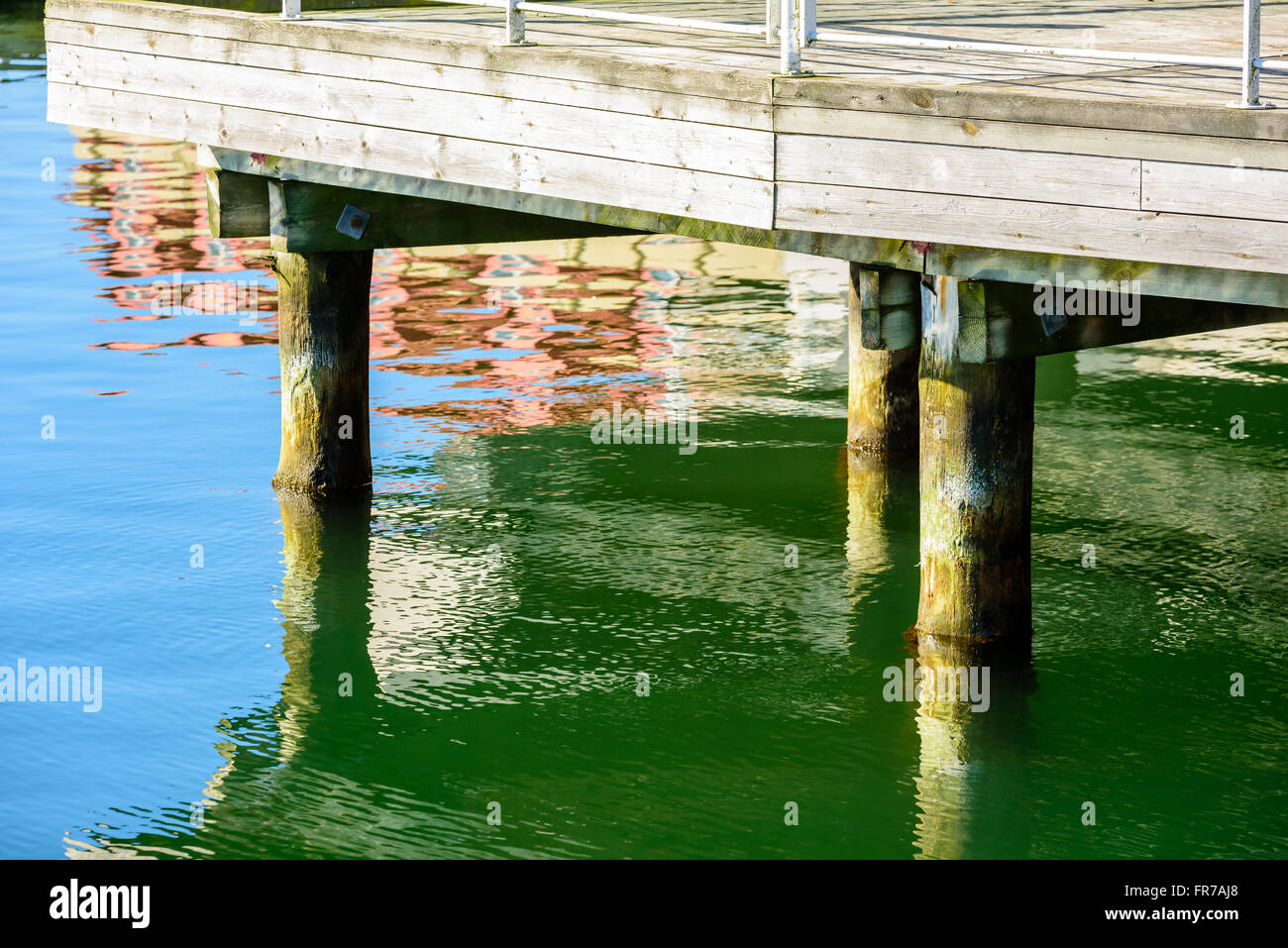 Some wooden pillars under a pier. Water is clam and still. Stock Photo