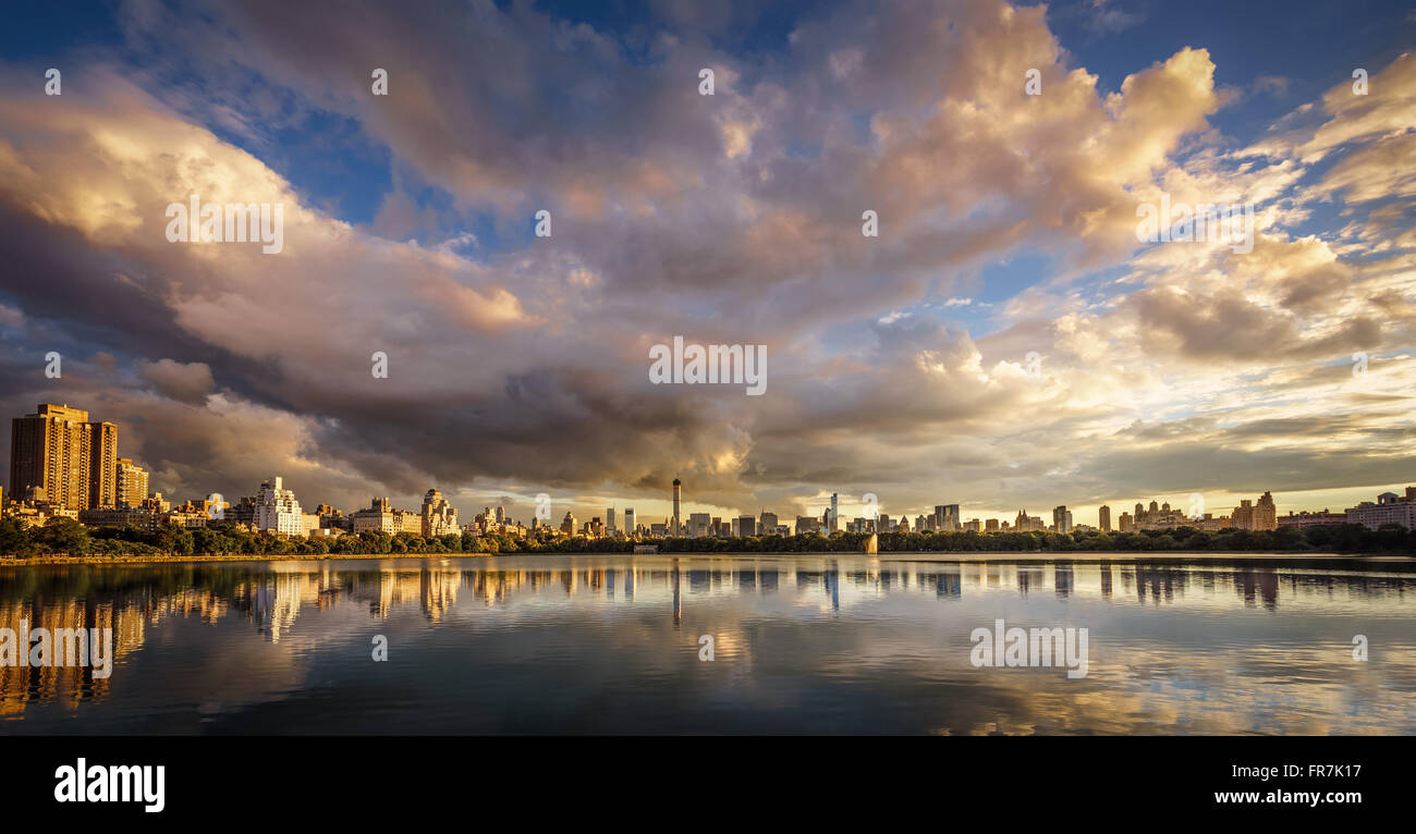 Sunset over Central Park Jacqueline Kennedy Onassis Reservoir with Manhattan skyline reflection and a cloudy sky. New York City Stock Photo