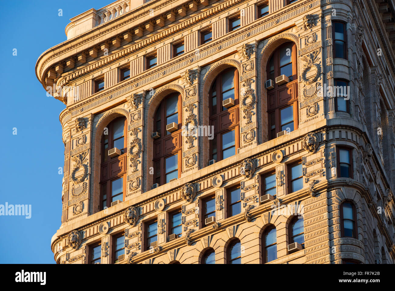 Flatiron Building (Beaux-Arts style) south facade at sunset showcasing intricate terracotta ornaments. Midtown, New York City Stock Photo