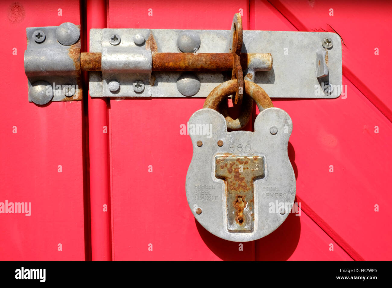 padlock on brightly red painted wooden doors uk Stock Photo
