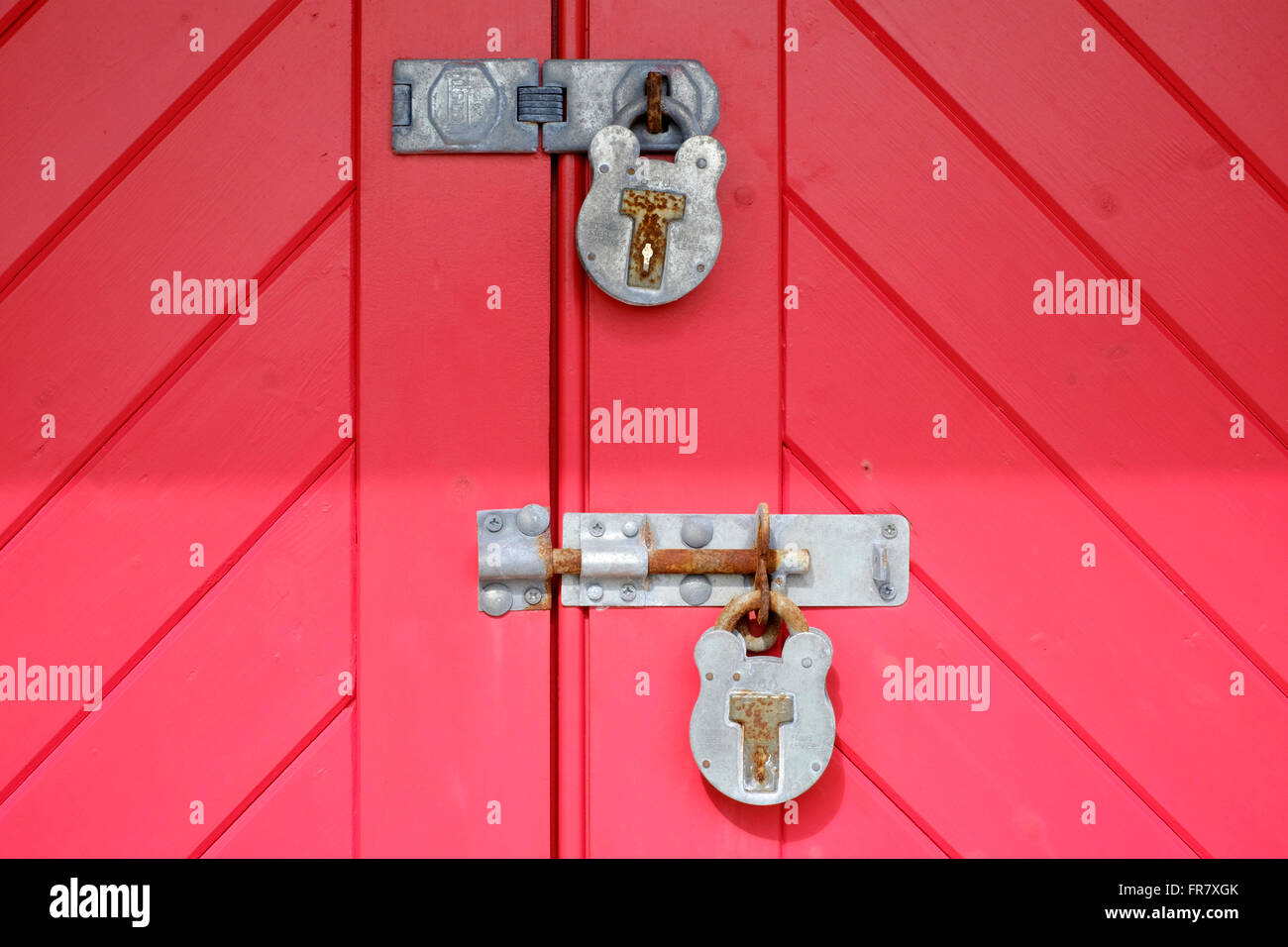padlocks on brightly red painted wooden doors uk Stock Photo