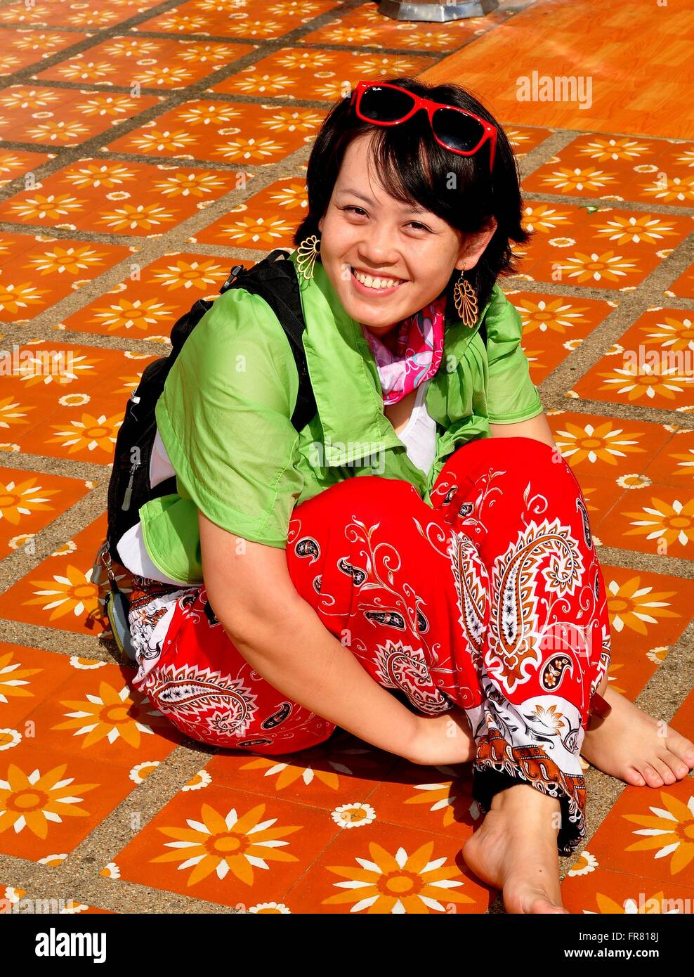 Chiang Mai, Thailand:  Smiling Thai woman sitting on a decorative tile floor at Wat Doi Suthep Stock Photo