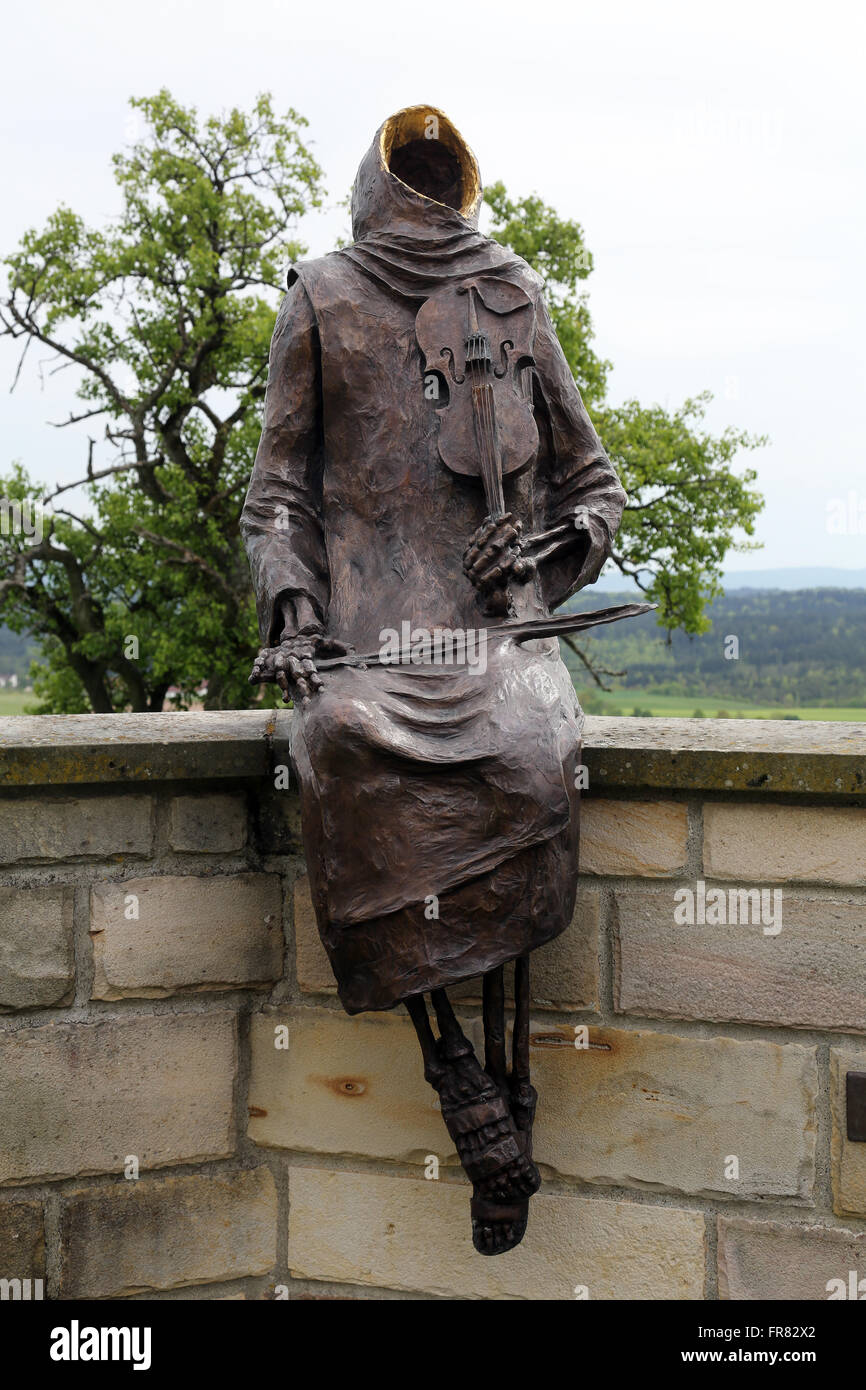 Monk Maurus with a violin sitting on the wall around the church in parish church of St. James in Hohenberg, Germany Stock Photo