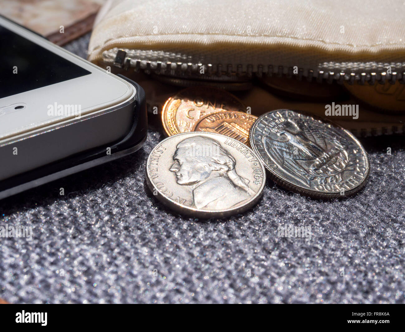 US dollar coins placed outside the wallet with smartphone. Stock Photo