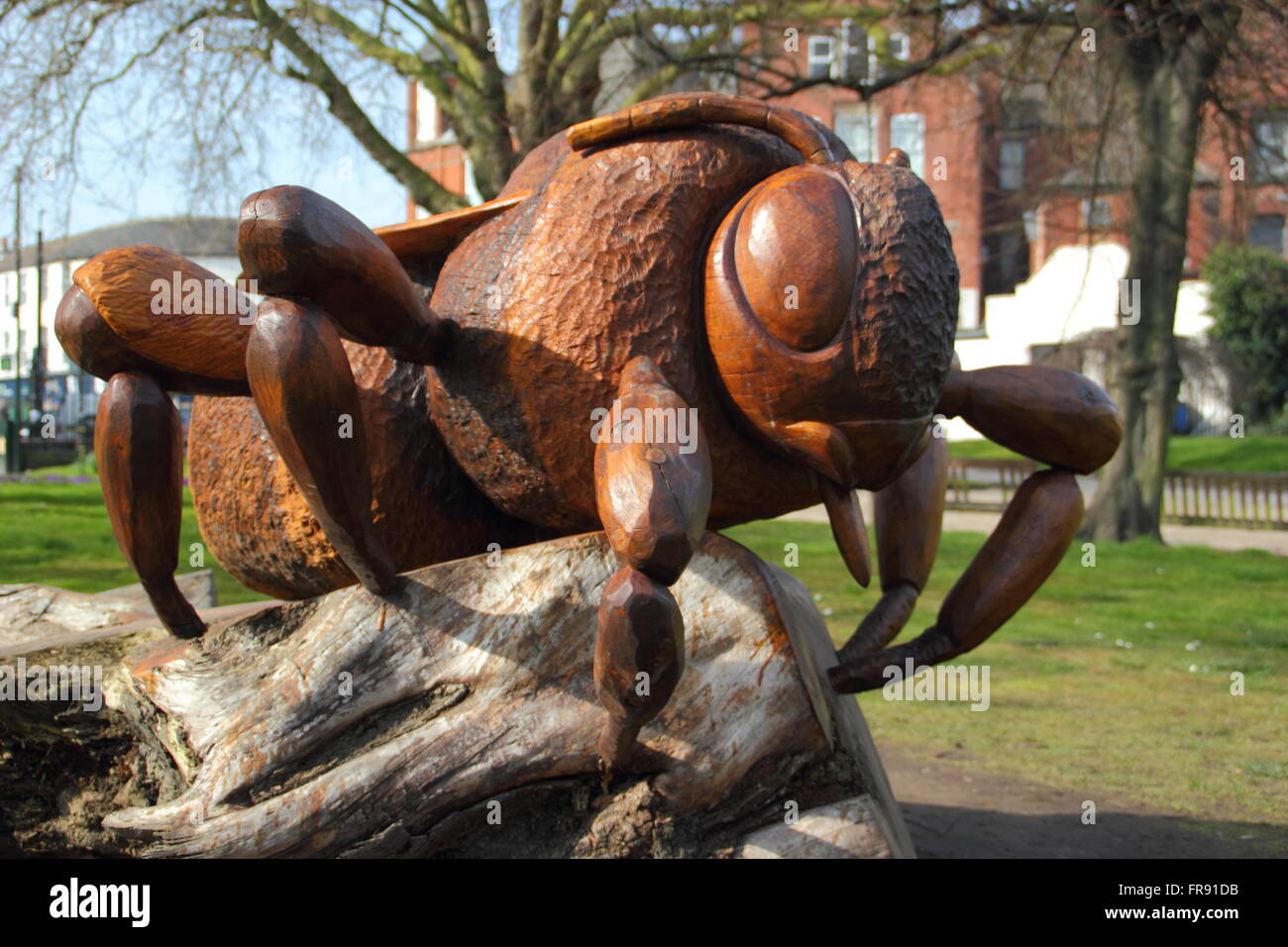 A wooden queen bee sculpture shaped from a fallen elm tree by artist, Andrew Frost to mark the insect's role as a pollinator, UK Stock Photo
