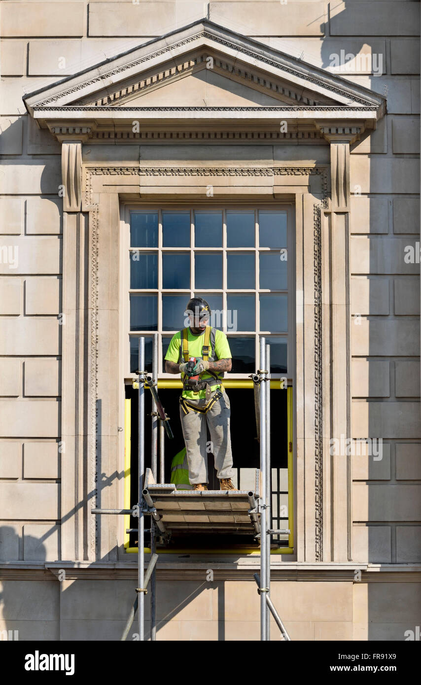 London, England, UK. Workman on scaffolding by a government building in Whitehall Stock Photo