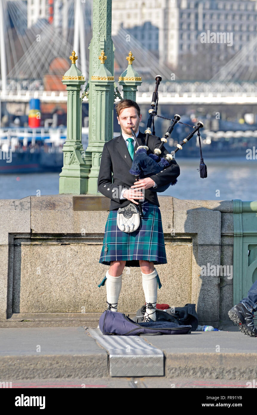 London, England, UK. Busker playing the bagpipes on Westminster Bridge