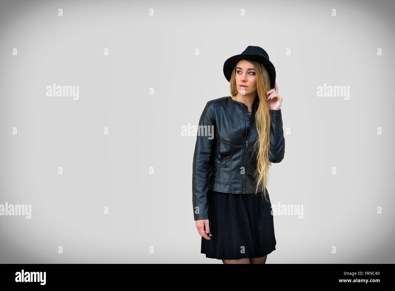 Portrait of attractive blonde woman in black hat and leather jacket looking at camera Stock Photo