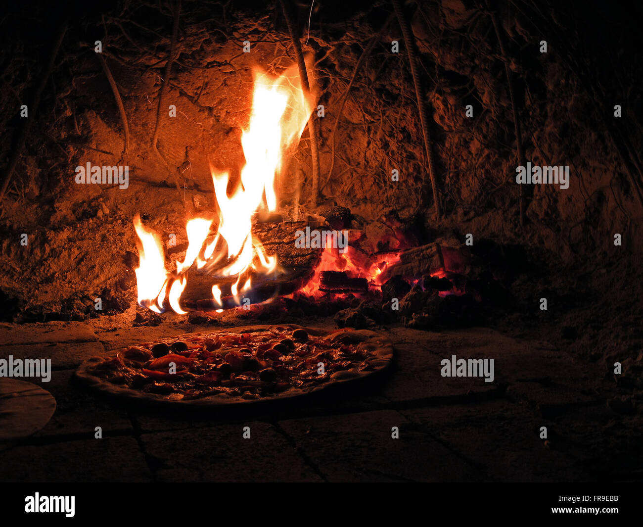 Pizza being baked in an oven made of clay mound according to local tradition Stock Photo