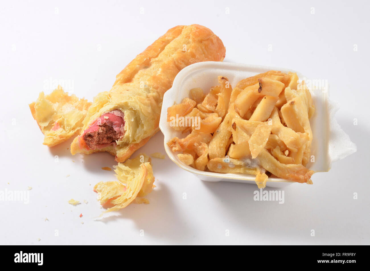Rotten old potato chips and a sausage roll with bacteria and mold showing on it. Stock Photo