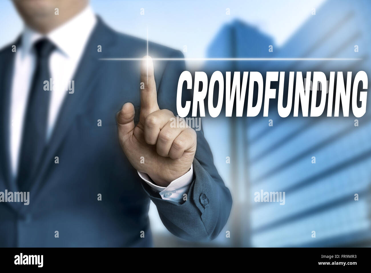 crowdfunding touchscreen is operated by businessman background. Stock Photo