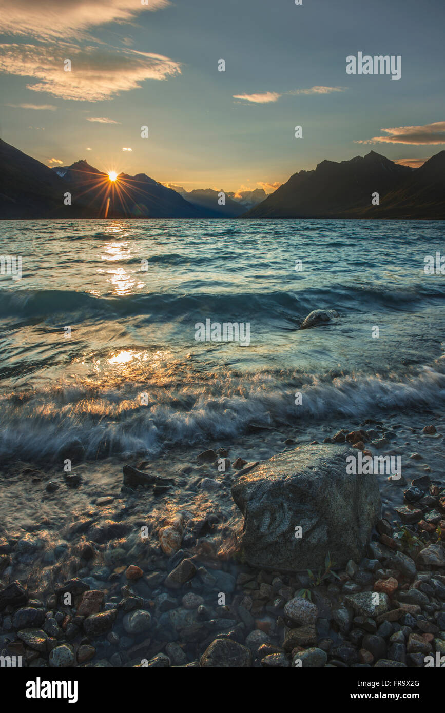 The sun rises as soft waves brush the shoreline of upper Twin Lake in Lake Clark National Park