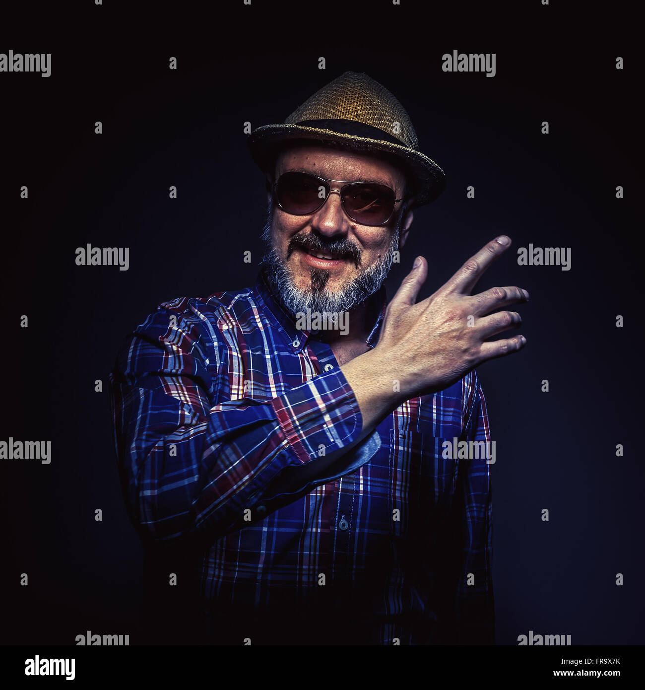 Portrait of a middle age man with hat and plaid shirt, showing something. Stock Photo