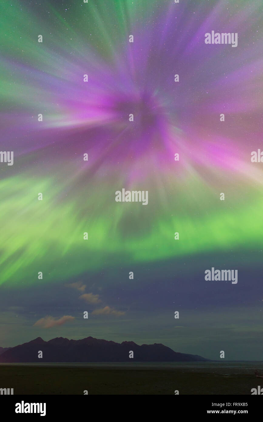 The aurora borealis bursts over the Kenai Mountains and the mudflats of