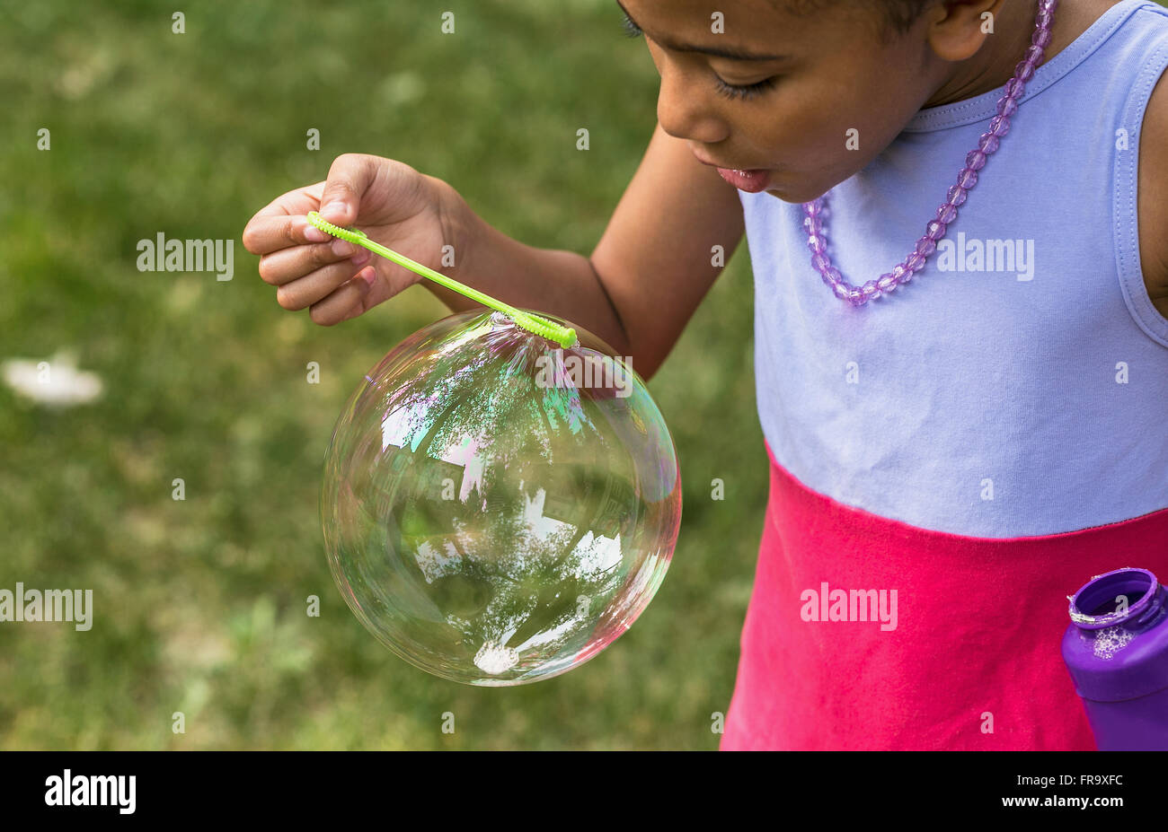 Young girl blowing a large bubble through a bubble wand; Edmonton