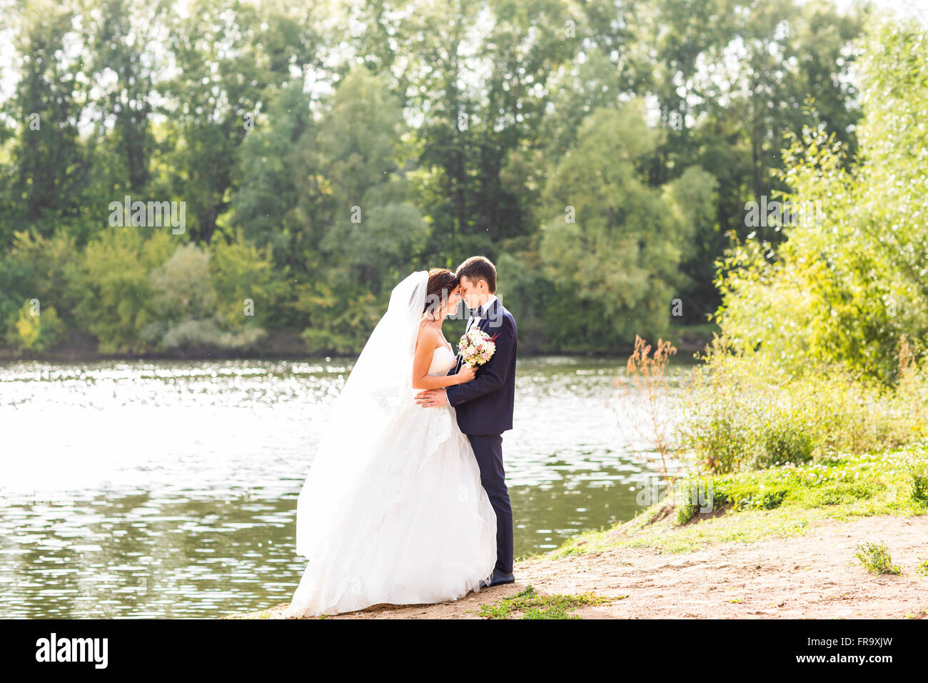Wedding couple standing and hugging near lake Stock Photo - Alamy