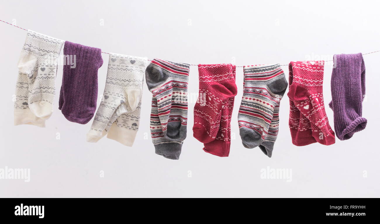 Various socks hanging from a wire indoors Stock Photo