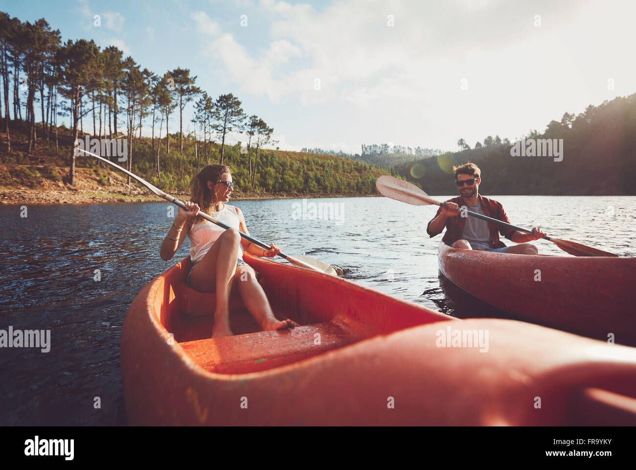 Young couple kayaking on a lake. Young kayakers rowing on lake on summer day. Stock Photo