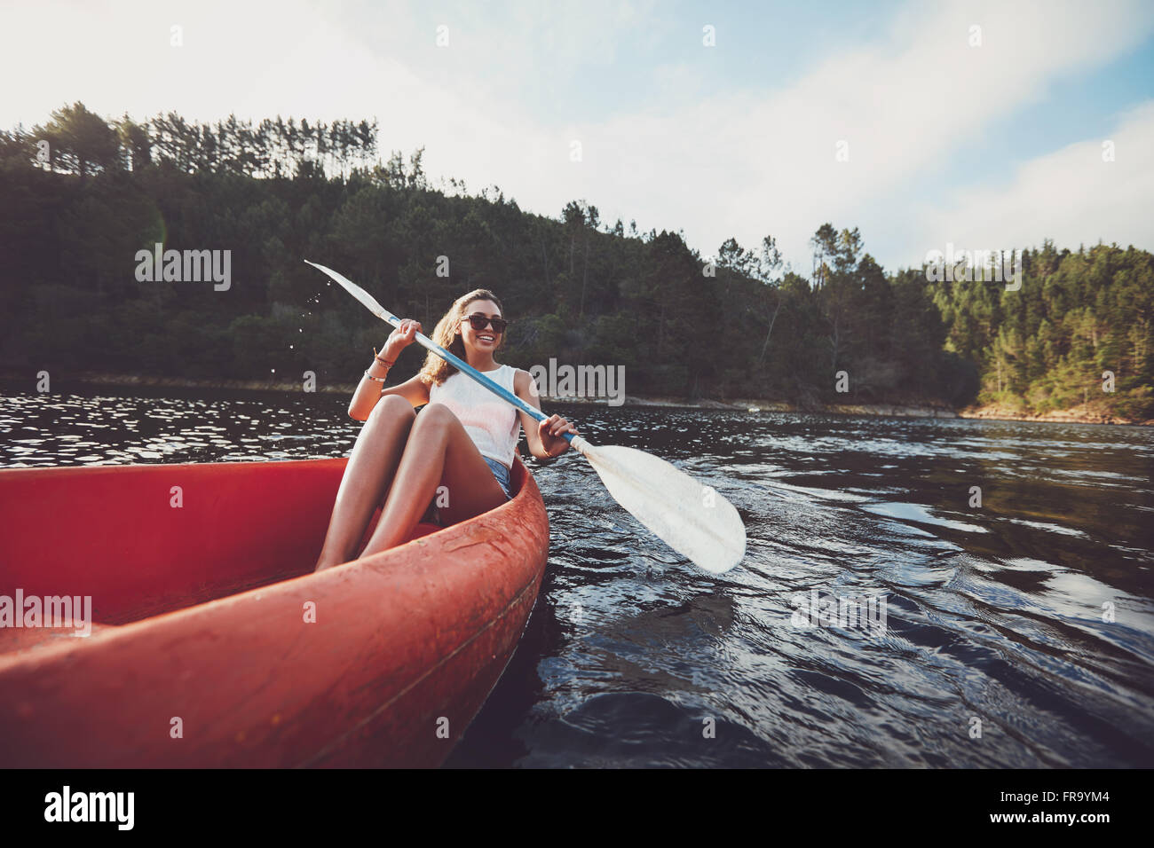 Young woman kayaking on a lake. Happy young woman canoeing in a lake. Stock Photo