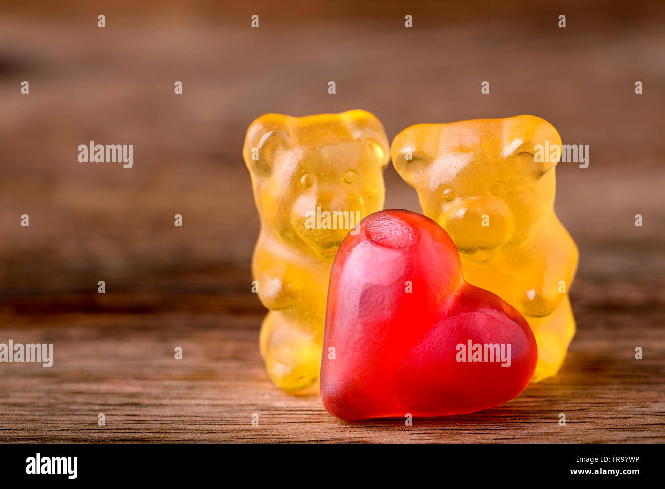 macro two yellow gummy bears with red hearts on wood Stock Photo