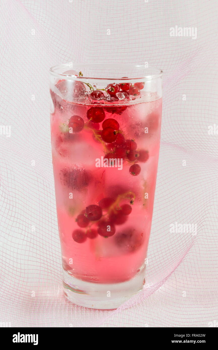 Berry fruit juice with ice cubes against soft pink background Stock Photo