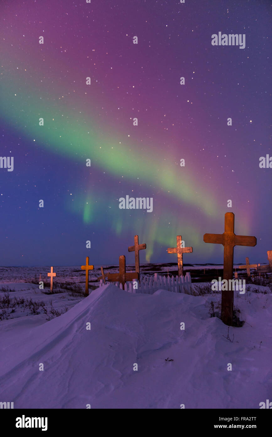 The aurora borealis colors the sky above crosses catching the light of dusk at Cemetery Hill in Kotzebue, Alaska. Stock Photo