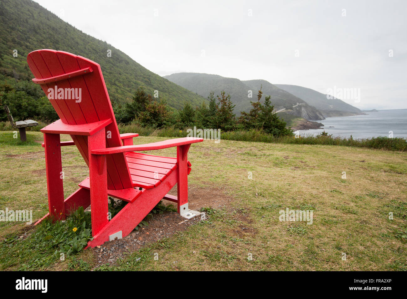 red muskoka chair overlooking Atlantic Ocean in nova scotia canada