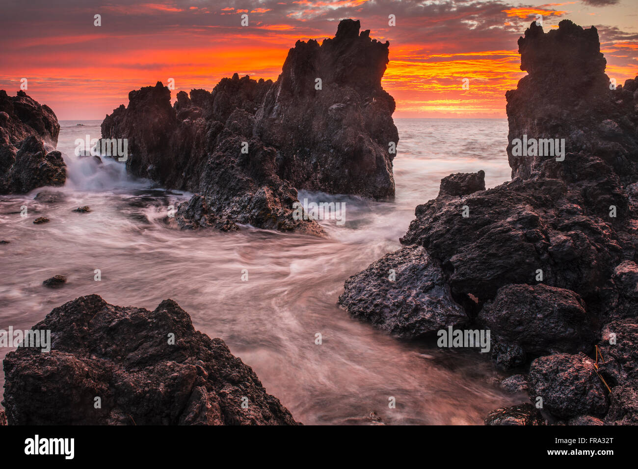 The colours of sunrise behind coastal lava rocks; Laupahoehoe, Island of Hawaii, Hawaii, United States of America Stock Photo