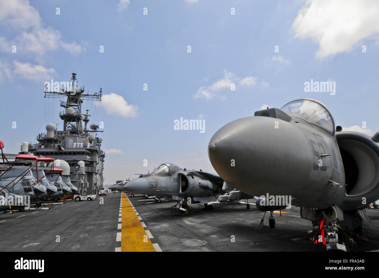 The nose of an AV-8B Marine Harrier II sticks out among other Harriers and a row of CH-46 Sea Knight helicopters onboard the USS Peleliu (LHA-5) Stock Photo
