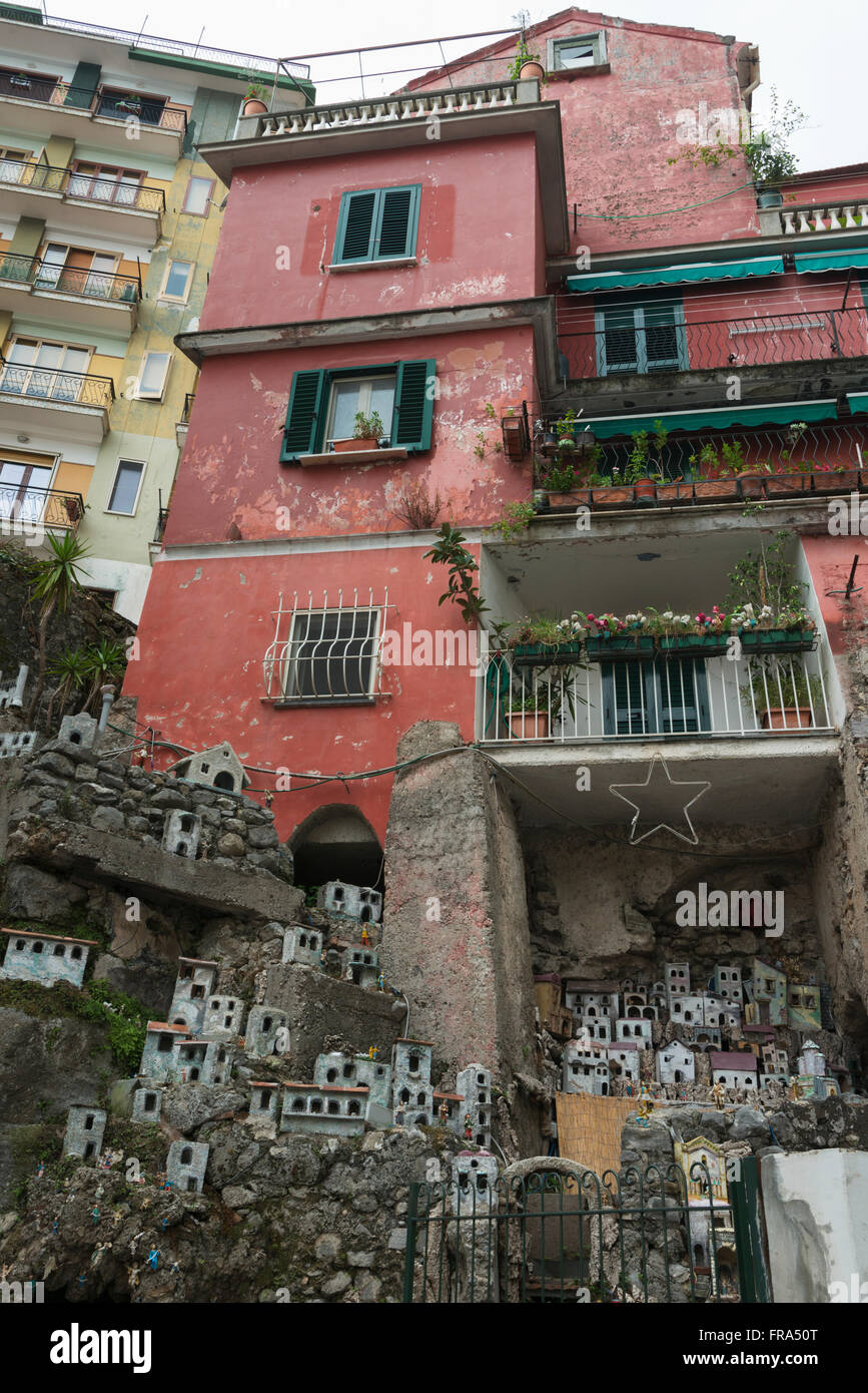 Low angle view of red and yellow residential buildings with a miniature sized display of houses in a community; Amalfi, Campania, Italy Stock Photo