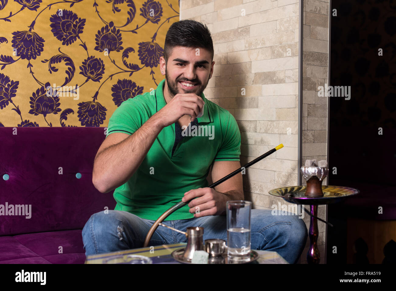 Uomo in completo relax nel bar shisha mentre fumare narghilè Foto stock -  Alamy