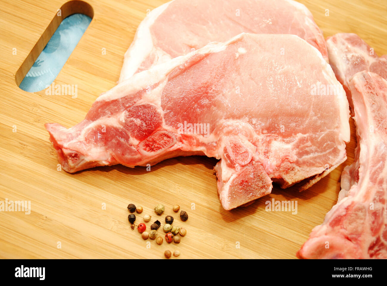 Pork Chops with Whole Peppercorns on a Wooden Cutting Board Stock Photo
