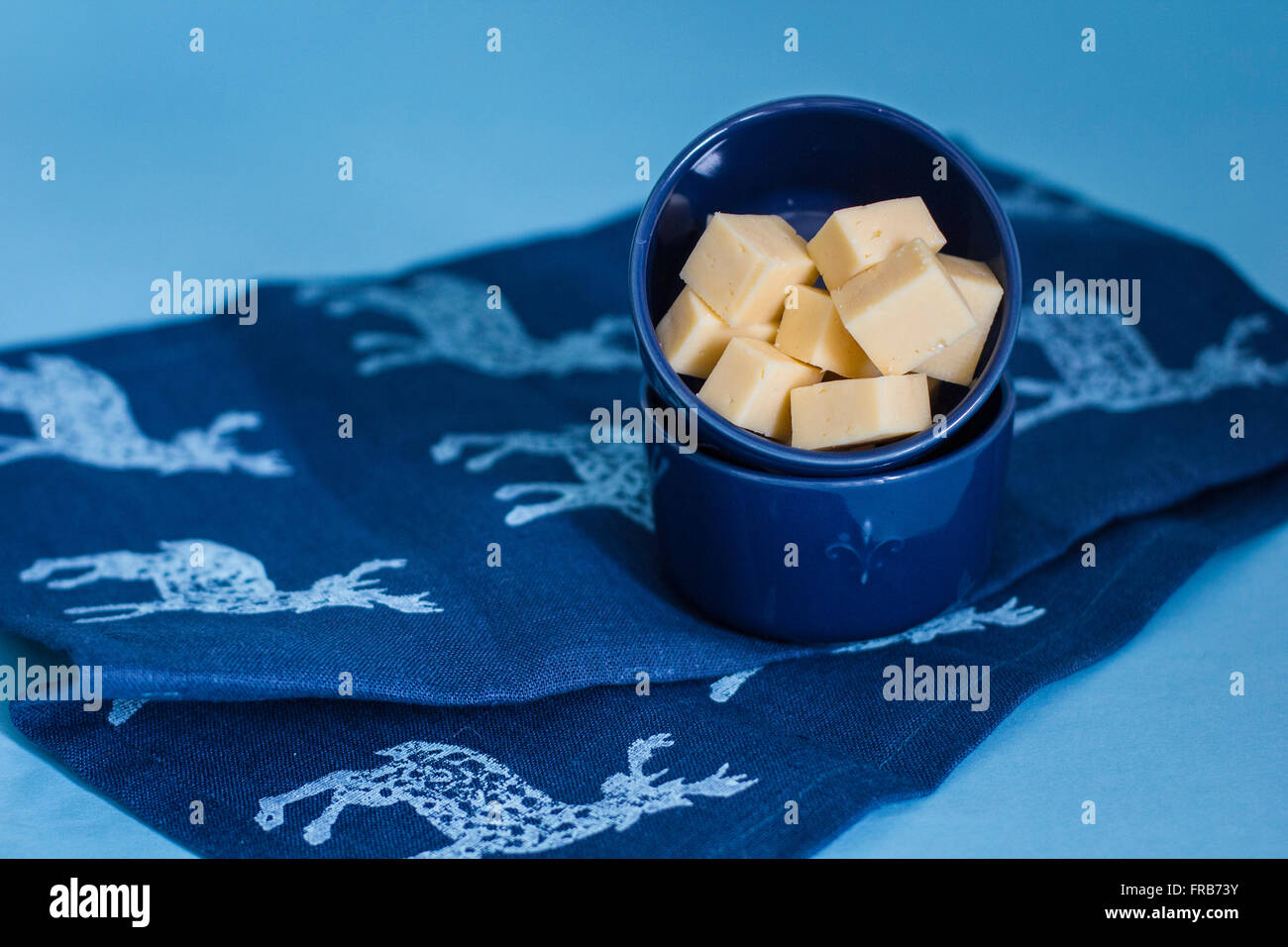 Cubes of cheese on blue background Stock Photo - Alamy
