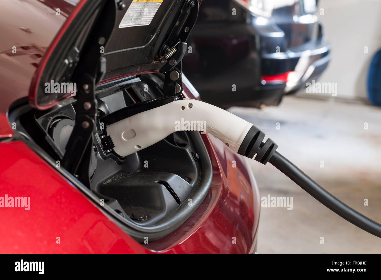 Electric car charging in a house garage with home charger. Stock Photo