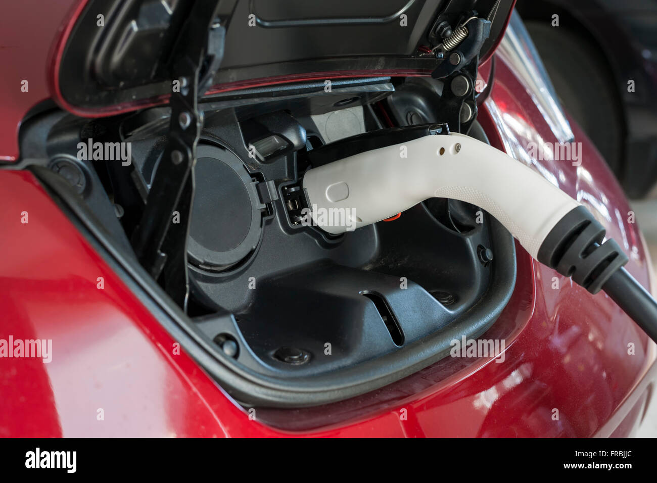 Electric car charging in a garage with home charger, close up. Stock Photo
