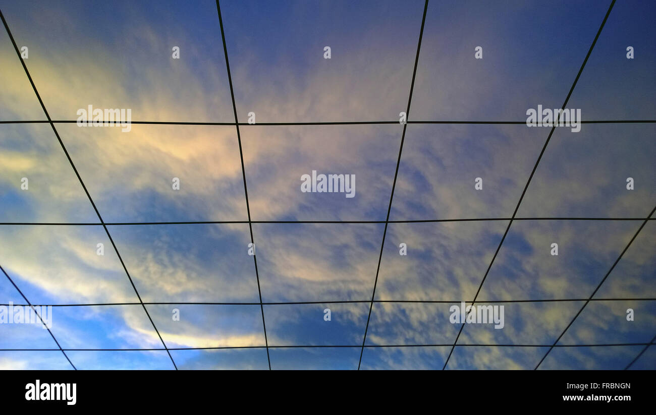 Sky with clouds in the late afternoon summer seen through grid Stock Photo