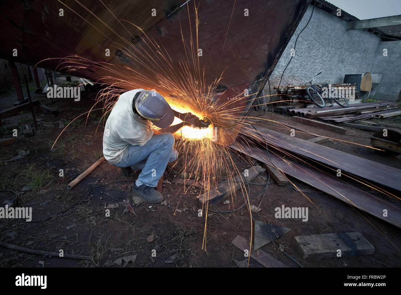 Worker sanding with emery sheet metal in small yard Stock Photo Alamy